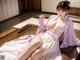 A woman in a pink kimono sitting on a wooden floor.