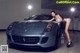 A woman in a bikini leaning on a car.