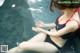 A woman in a black and red bikini sitting in a pool of water.