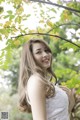 A woman in a white dress standing under a tree.