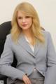 A woman in a business suit sitting on a chair.