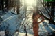 A naked woman standing in the snow in the woods.