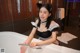 A woman in a maid outfit sitting in a bathtub.