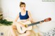 A woman sitting on a bed holding a guitar.