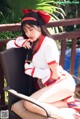 A woman in a red and white outfit sitting on a chair.