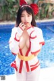 A woman in a red and white outfit posing by a pool.