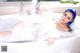 A woman with blue hair is taking a bath in a bathtub.