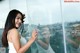 A woman standing in front of a glass wall with a city view.